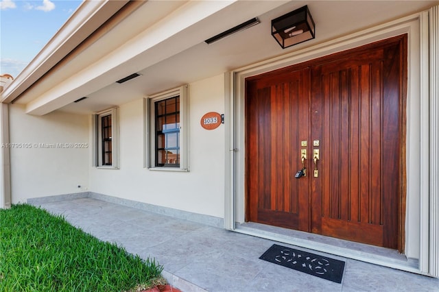 entrance to property featuring visible vents and stucco siding