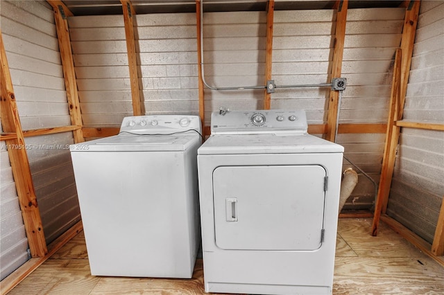 laundry area with laundry area, wood walls, and washer and dryer