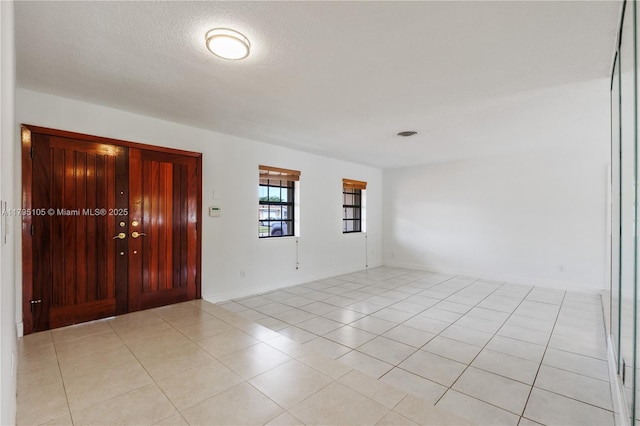 entryway featuring baseboards, a textured ceiling, and light tile patterned floors
