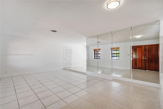 empty room with light tile patterned floors and baseboards