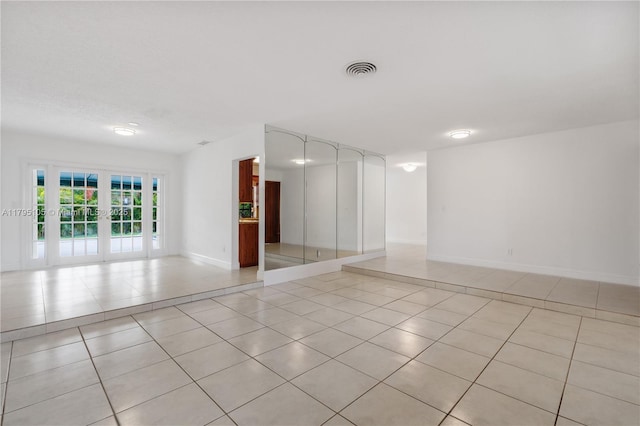 spare room featuring baseboards, visible vents, and light tile patterned floors