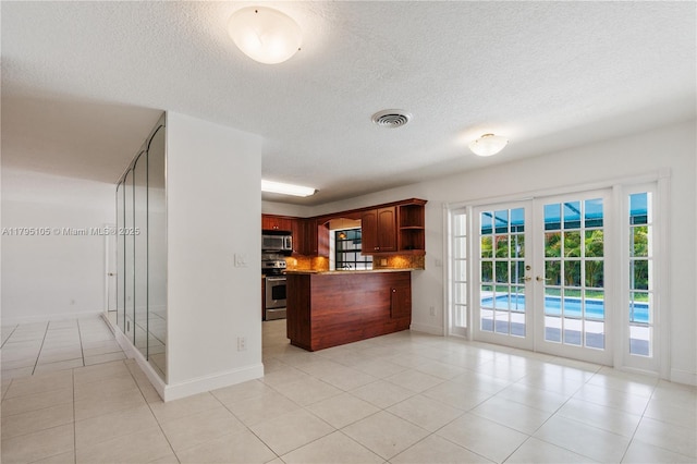 kitchen featuring appliances with stainless steel finishes, a textured ceiling, french doors, light tile patterned floors, and visible vents