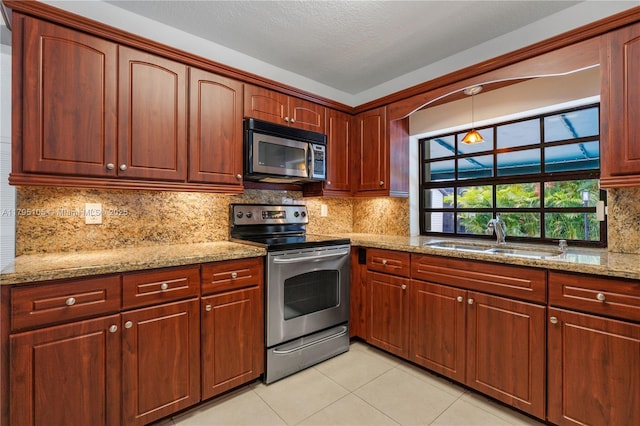 kitchen featuring backsplash, appliances with stainless steel finishes, a sink, light tile patterned floors, and light stone counters