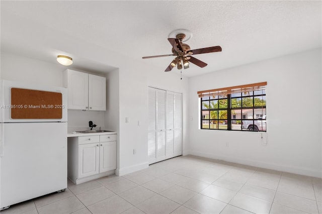 unfurnished room featuring a ceiling fan, baseboards, a sink, and light tile patterned flooring