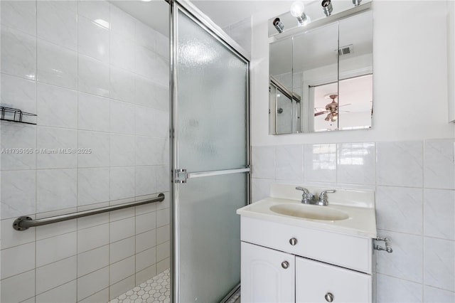 full bath featuring vanity, a stall shower, tile walls, and visible vents