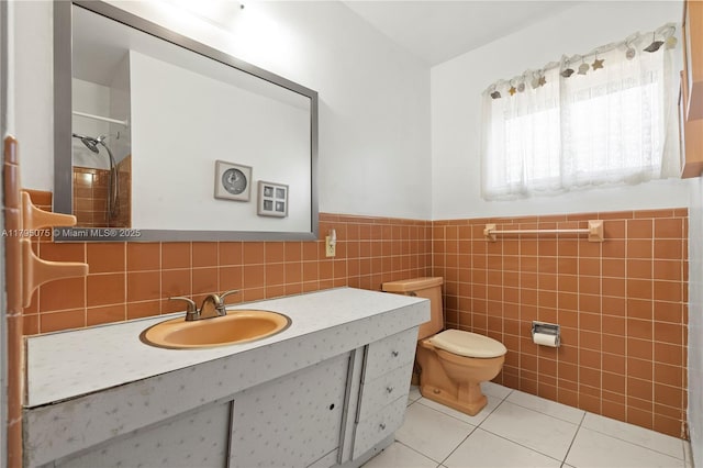 bathroom with tile patterned flooring, toilet, a wainscoted wall, tile walls, and a shower