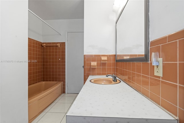 bathroom with tile patterned flooring, tile walls, shower / tub combination, a wainscoted wall, and a sink