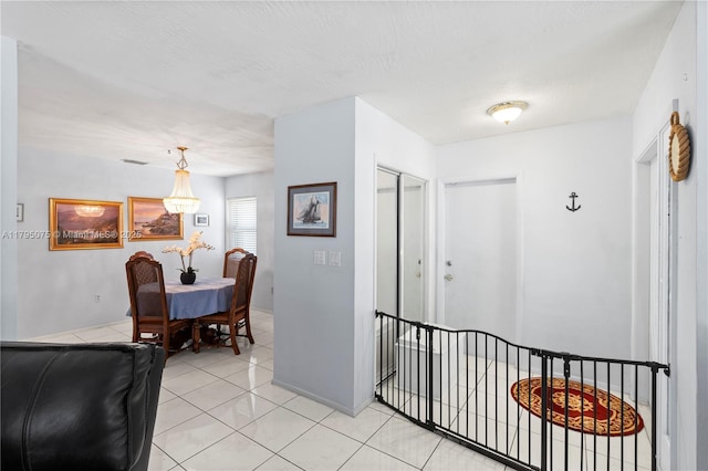 corridor featuring an inviting chandelier and light tile patterned flooring