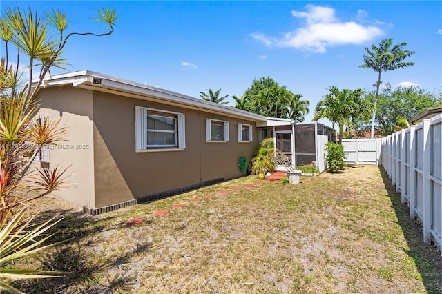 rear view of house with a fenced backyard, stucco siding, and a yard