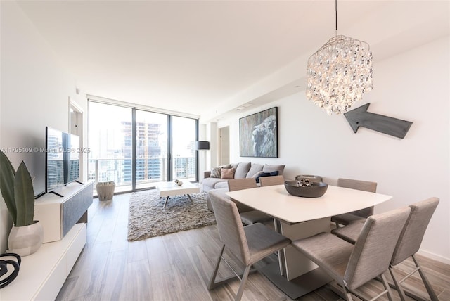 dining area with light wood finished floors, a notable chandelier, and a wall of windows