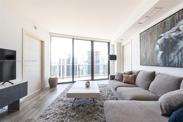 living area featuring expansive windows, a view of city, baseboards, and wood finished floors