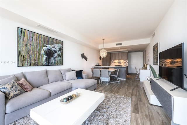 living room featuring a notable chandelier, dark wood-style floors, and visible vents