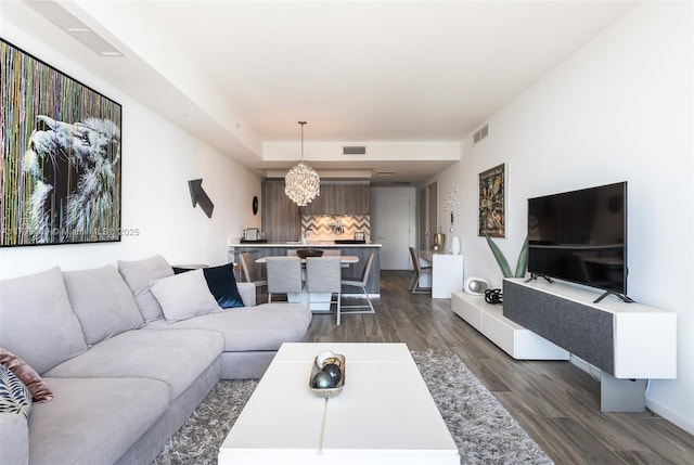 living area featuring visible vents, dark wood-style flooring, baseboards, and a notable chandelier