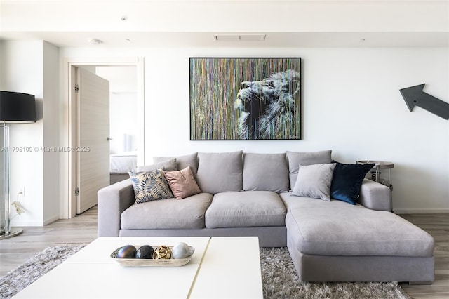 living area with light wood-style floors, baseboards, and visible vents
