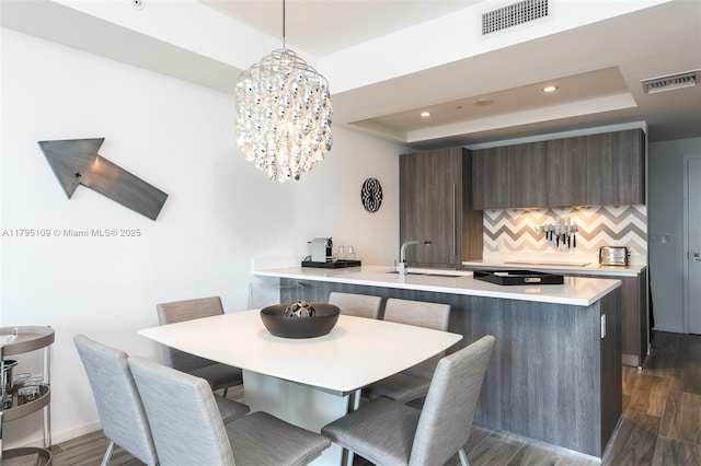 dining area with a tray ceiling, dark wood-type flooring, and visible vents