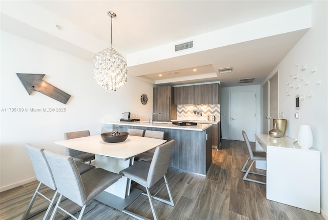 dining room with visible vents, a raised ceiling, a chandelier, recessed lighting, and dark wood-type flooring