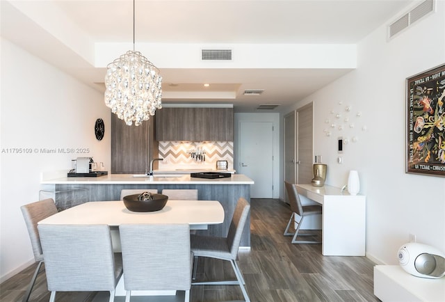 dining area featuring visible vents, a raised ceiling, and dark wood-type flooring