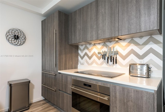 kitchen featuring light countertops, black electric cooktop, stainless steel oven, and modern cabinets