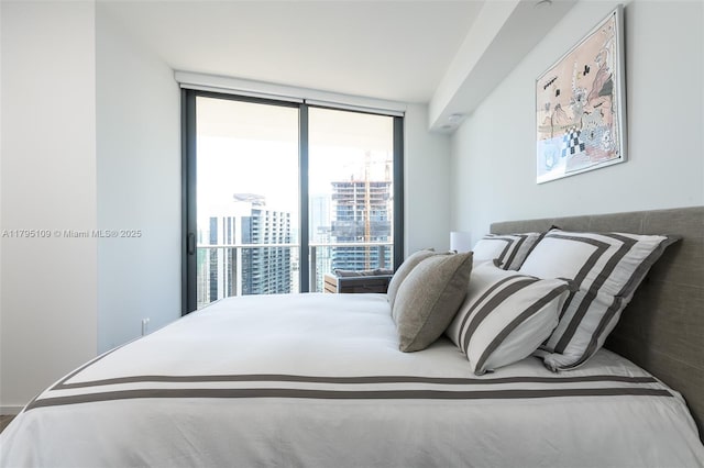 bedroom featuring a view of city and a wall of windows