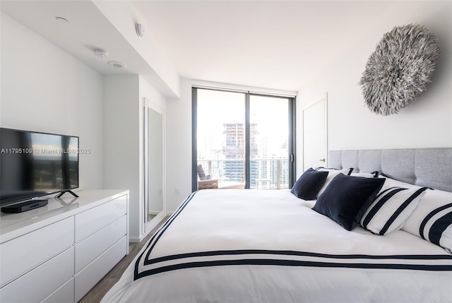 bedroom with expansive windows and wood finished floors