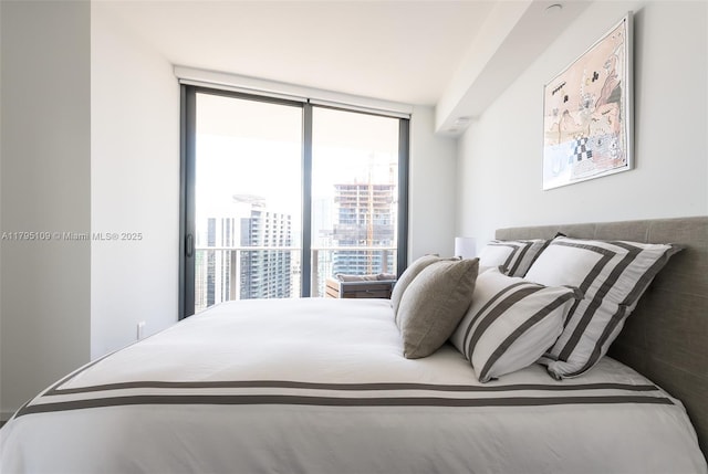 bedroom featuring a view of city and a wall of windows