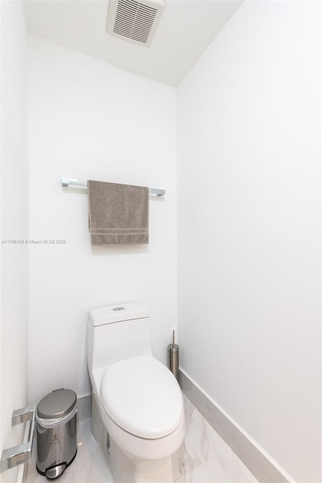 bathroom featuring toilet, baseboards, visible vents, and marble finish floor