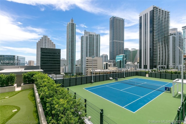 view of tennis court with fence and a view of city