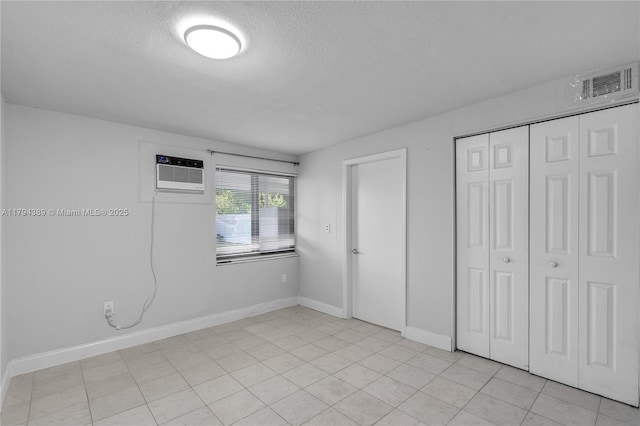 617 W 33rd St, Hialeah, FL 33012 - unfurnished bedroom with a textured ceiling, baseboards, a wall unit AC, visible vents, and a closet