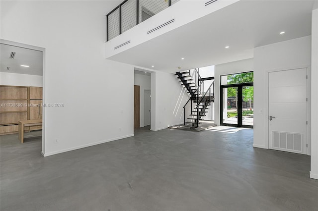 2730 SW 17th Ave, Miami, FL 33133 - unfurnished living room with visible vents, stairs, baseboards, a high ceiling, and concrete floors