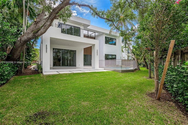 2730 SW 17th Ave, Miami, FL 33133 - back of house featuring fence, a balcony, stucco siding, a patio area, and a lawn