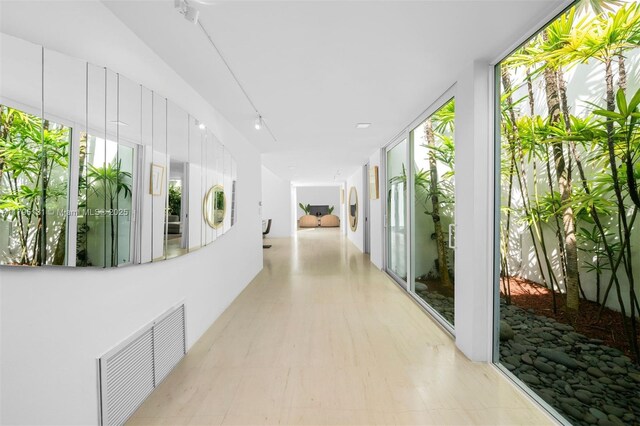 hallway with expansive windows, visible vents, and a wealth of natural light