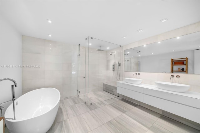 full bathroom with double vanity, a freestanding bath, a shower stall, and a sink