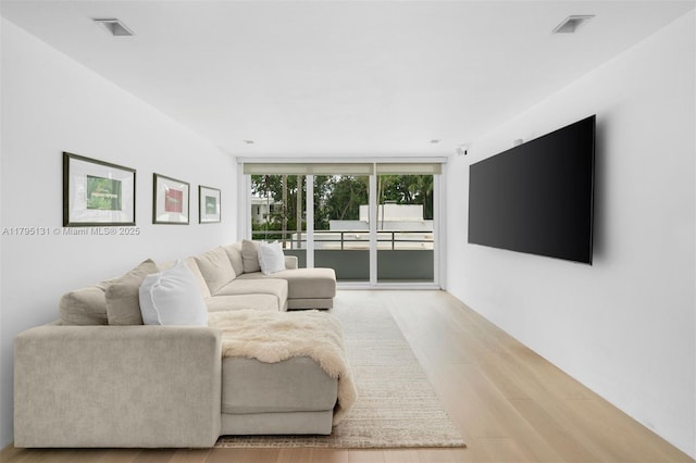 living area with expansive windows, light wood-style flooring, and visible vents