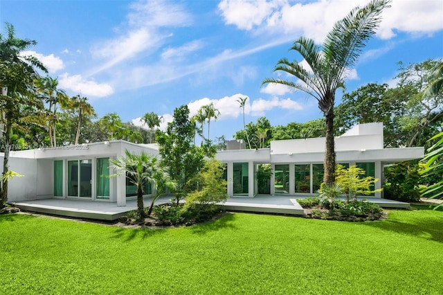 rear view of property featuring stucco siding and a yard