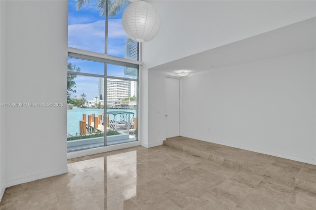 171 N Shore Dr Unit 171-1, Miami Beach, FL 33141 - empty room featuring a water view, baseboards, and a towering ceiling