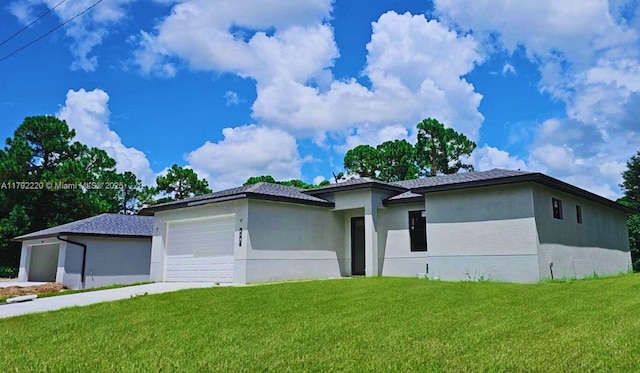 prairie-style home with an attached garage, a front lawn, stucco siding, and driveway