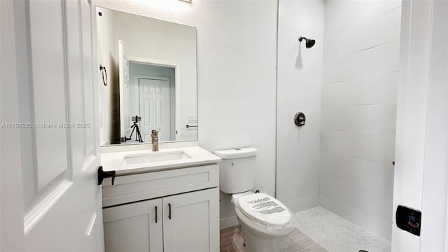 bathroom featuring toilet, tiled shower, and vanity