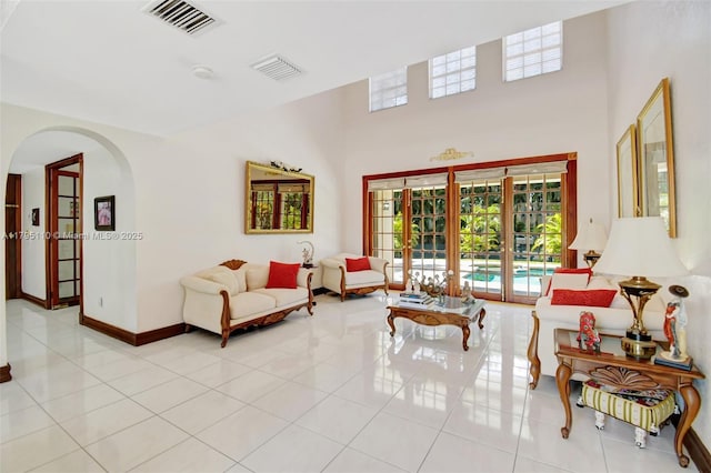 12360 SW 1st St, Plantation, FL 33325 - living area with arched walkways, french doors, light tile patterned flooring, a high ceiling, and baseboards