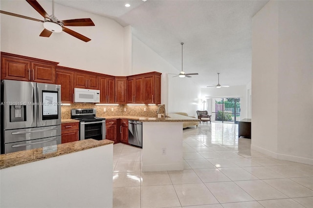 9751 Malvern Dr, Tamarac, FL 33321 - kitchen with high vaulted ceiling, stainless steel appliances, a ceiling fan, a peninsula, and backsplash