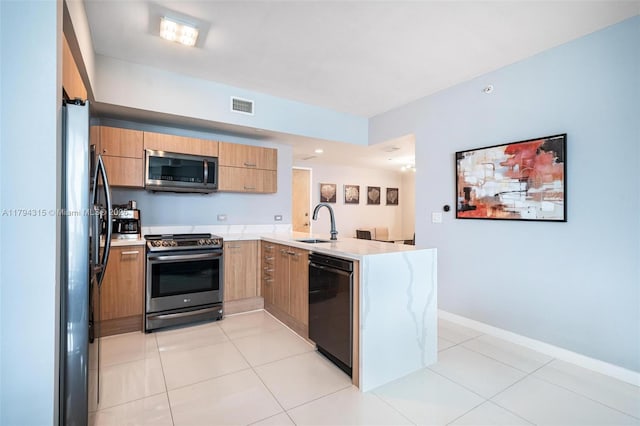 kitchen featuring visible vents, modern cabinets, a sink, black appliances, and a peninsula