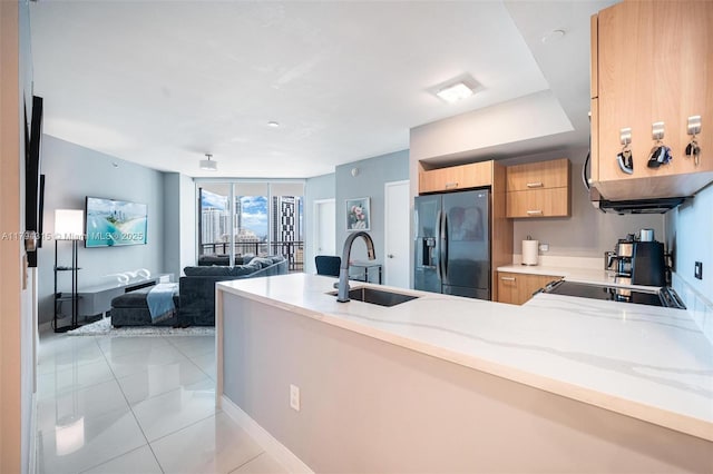 kitchen with modern cabinets, a sink, light stone counters, light tile patterned floors, and black refrigerator with ice dispenser