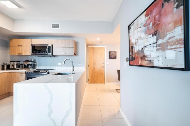 kitchen with visible vents, modern cabinets, a sink, light tile patterned floors, and stainless steel appliances