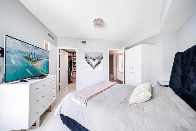 bedroom featuring a spacious closet, a closet, light tile patterned flooring, and visible vents