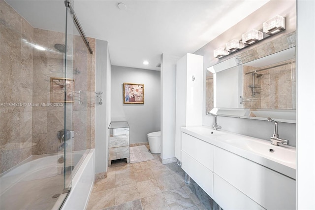 bathroom with double vanity, toilet, baseboards, bath / shower combo with glass door, and a sink