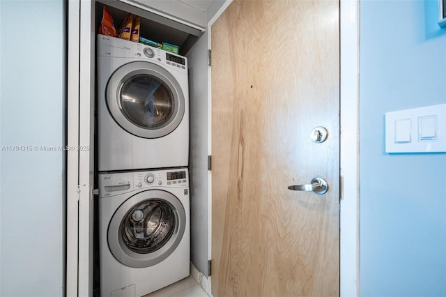laundry area featuring stacked washing maching and dryer, tile patterned flooring, and laundry area