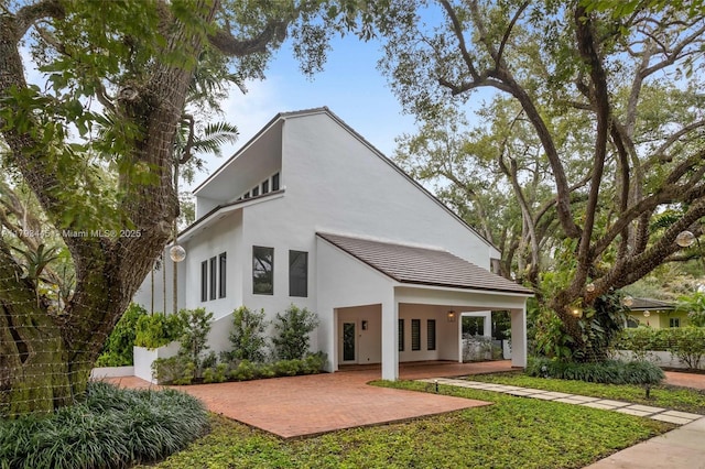 rear view of property with french doors, a patio, and stucco siding