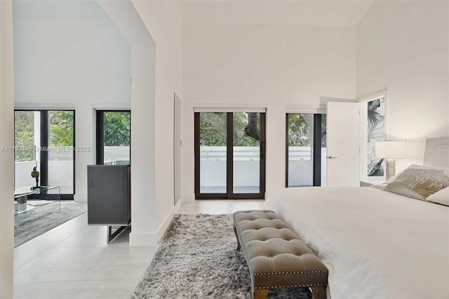 bedroom with access to outside, a high ceiling, and multiple windows