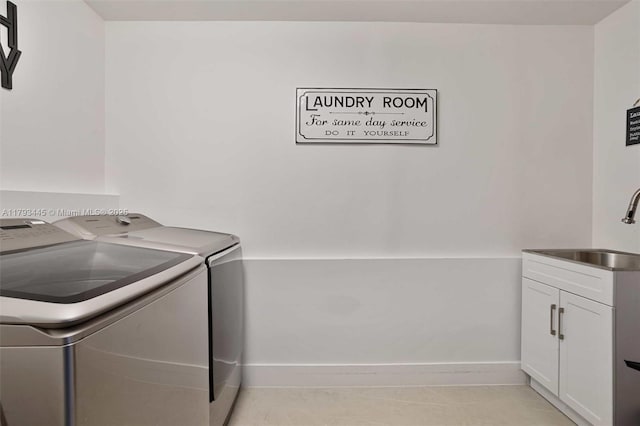 laundry room with a sink, baseboards, washing machine and dryer, and cabinet space