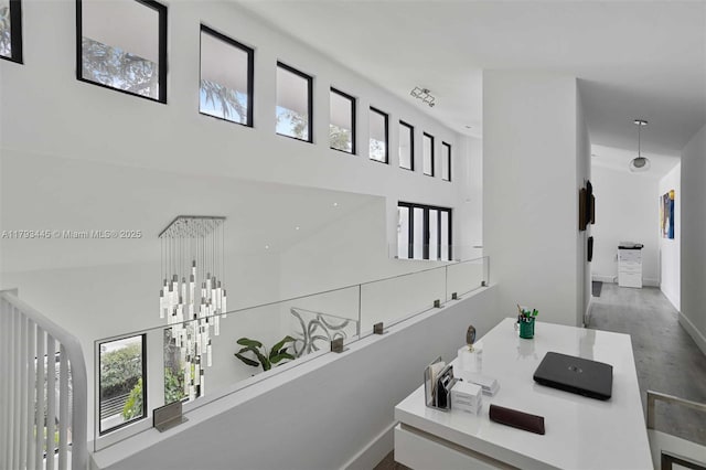 hallway with a healthy amount of sunlight, baseboards, a high ceiling, and wood finished floors
