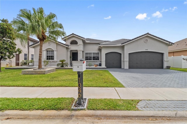mediterranean / spanish-style house with a tile roof, a garage, stucco siding, a front yard, and decorative driveway